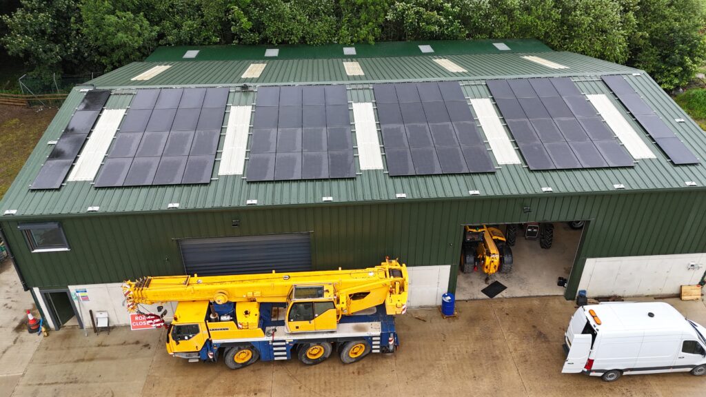 Aerial view of Park Hill Farm — the working fabrication and plant yard, with the rooftop solar array that powers the site, and a mobile crane, telehandler and van in the yard below